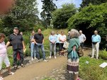 Eine Frau erzählt einer Gruppe Menschen etwas in einem Garten